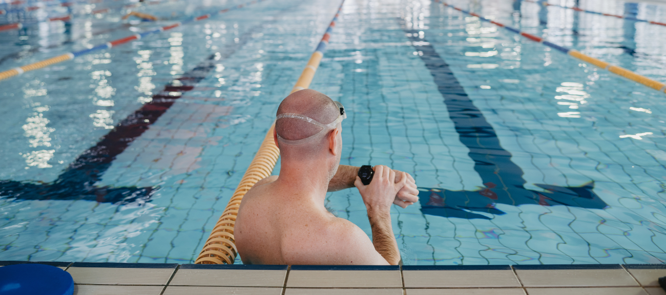 Picture of the back of a man's head. Man is checking his watch in the 50m pool at Aqualink Nunawading