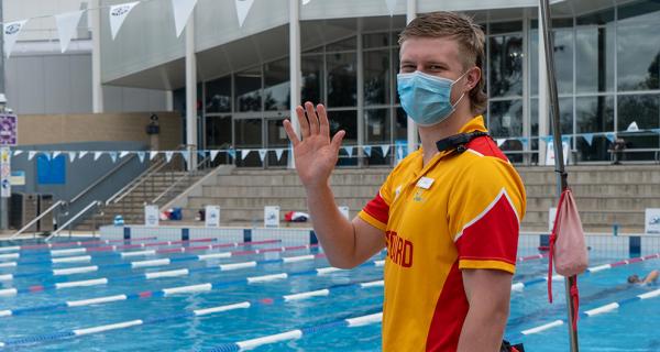 Lifeguard at outside pool welcoming you back with a wave