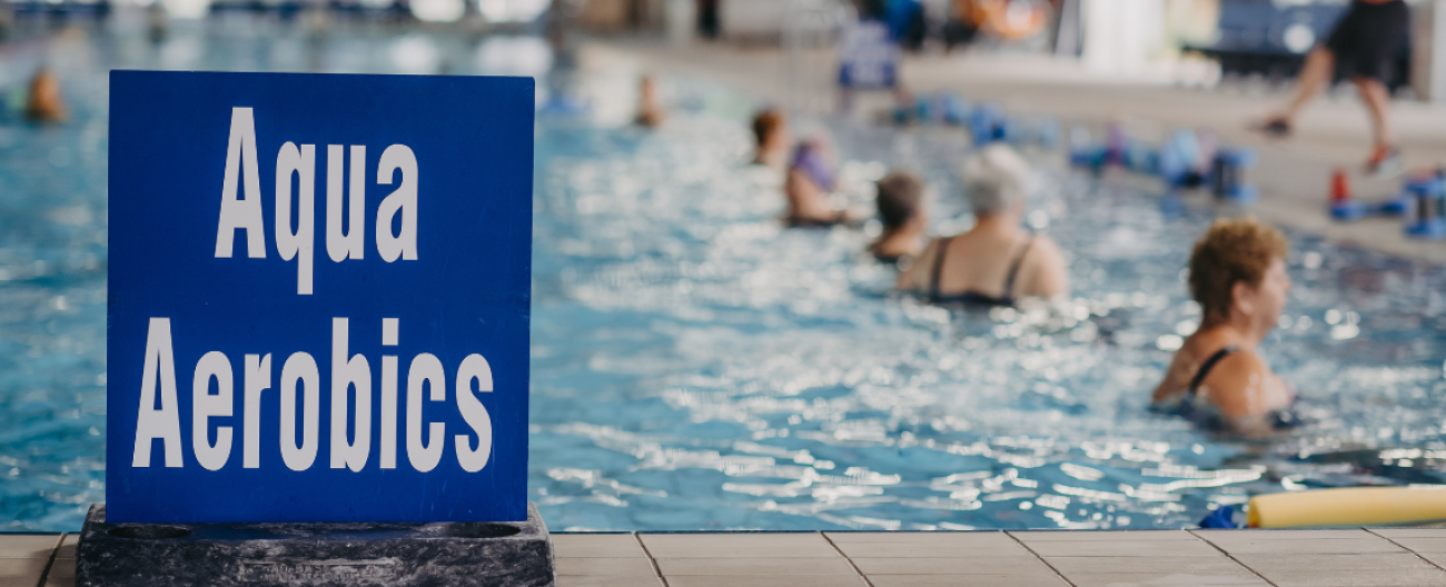 aQUA CLASS SIGN IN FOREGORUND WITH 50M POOL IN BACKGROUND